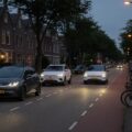 Moderne Chinese elektrische auto's rijden door een Nederlandse straat bij avondlicht