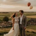 Modern Nederlands bruidspaar op een heuvel tijdens hun trouwdag 2026, lachend met ballonnen die wegdrijven – symbool voor romantiek en de realiteit van het huwelijk.