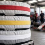 Gestapelde racebanden in bandenwarmers met rode, gele en witte banden in een pitgarage