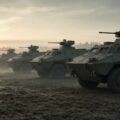 Rij militaire pantservoertuigen op een mistig oefenterrein bij zonsopkomst, als beeld bij de grootste legers ter wereld.